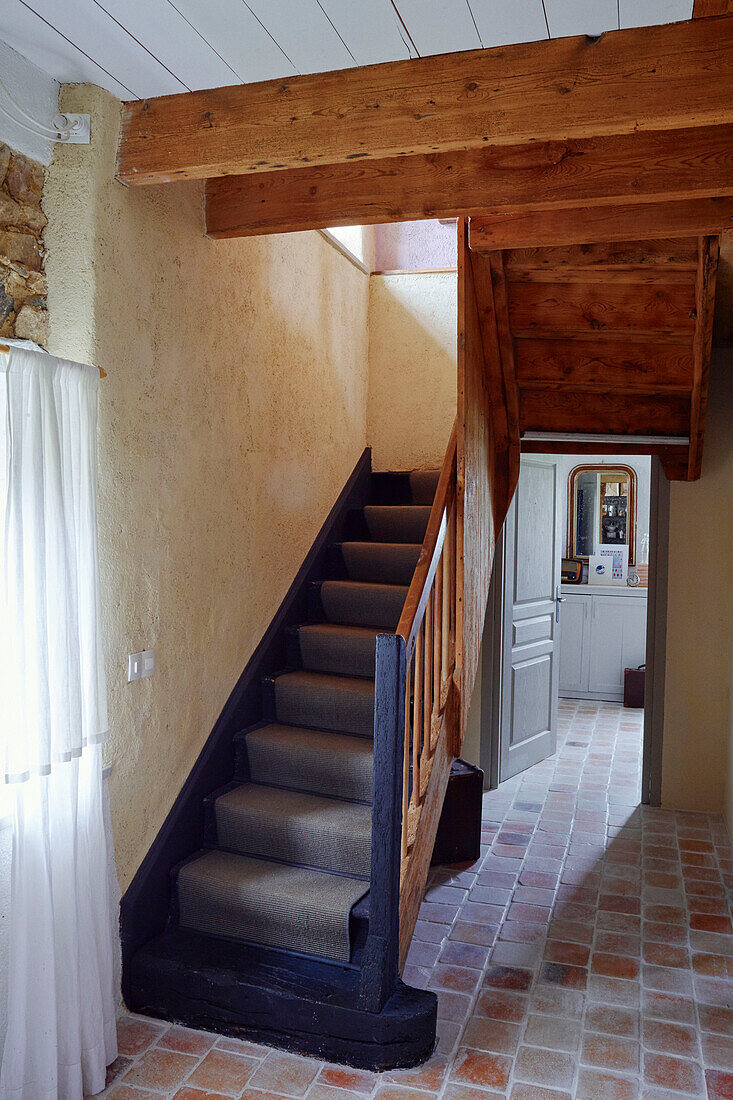 Graues Treppenhaus mit Teppichboden und Terrakottafliesen in einem bretonischen Landhaus in Frankreich