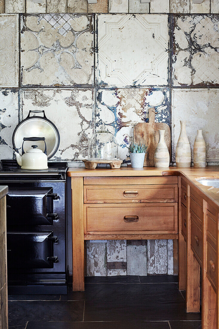 Wasserkocher auf dem Kochfeld mit Holzschubladen und Kacheln in einer Küche in Devon, UK
