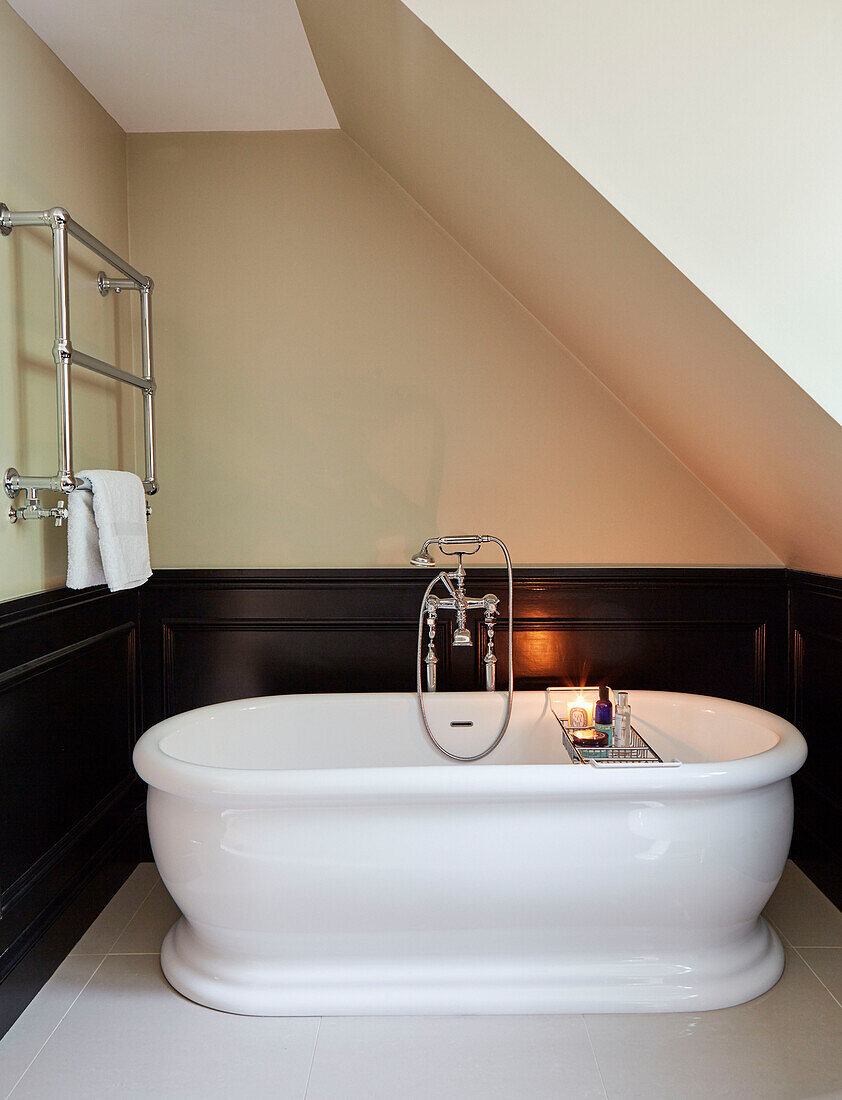 Weiße freistehende Badewanne mit wandmontiertem Handtuchhalter aus Chrom in einem Haus in Durham England, UK