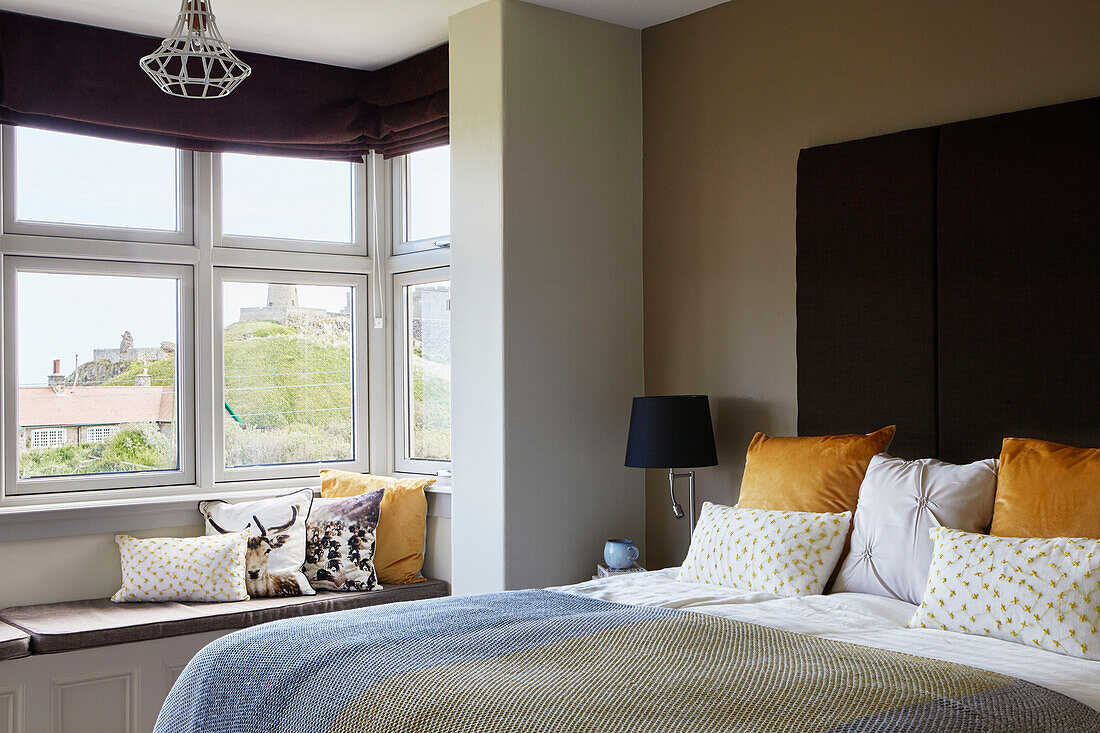Gelbe Samtkissen und Erkerfenster mit Blick auf das Meer im Schlafzimmer in Northumbrian, UK