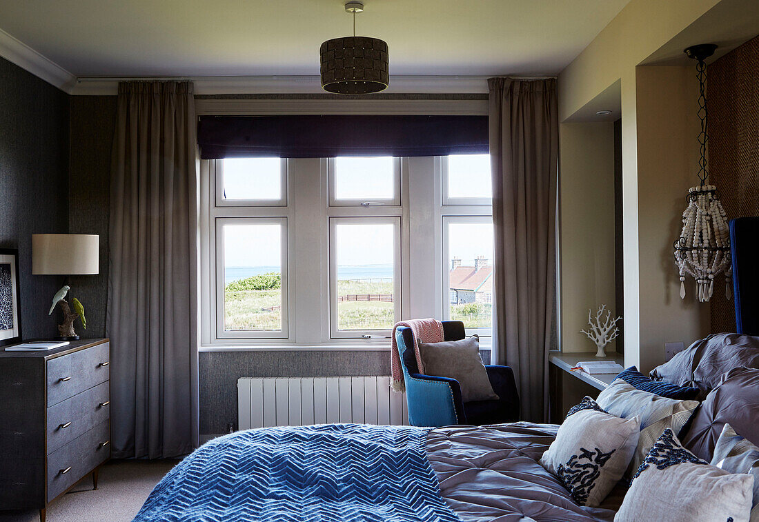 Ungemachtes Bett mit Blick auf das Meer in einem Haus in Northumbria, UK