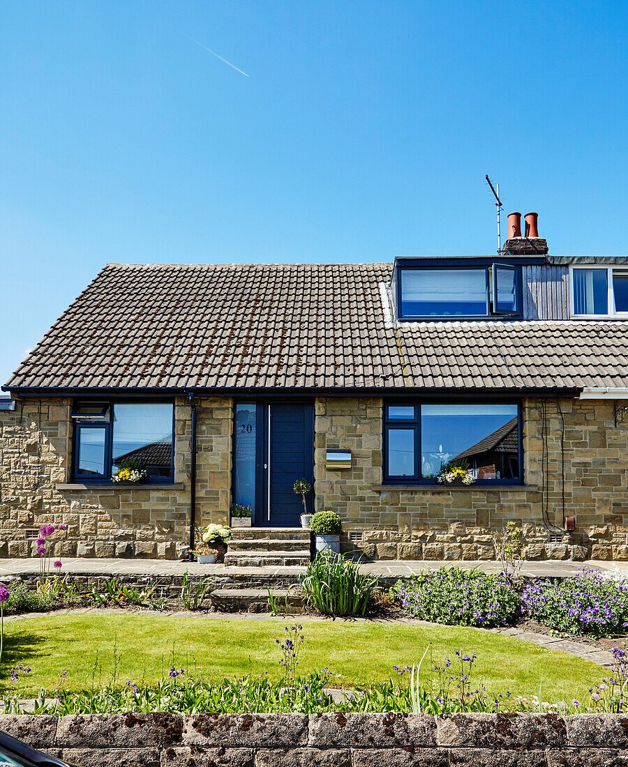 Eingangstür und Garten eines renovierten Bungalows mit Dachgaube aus den 1960er Jahren in Holmfirth, West Yorkshire, UK