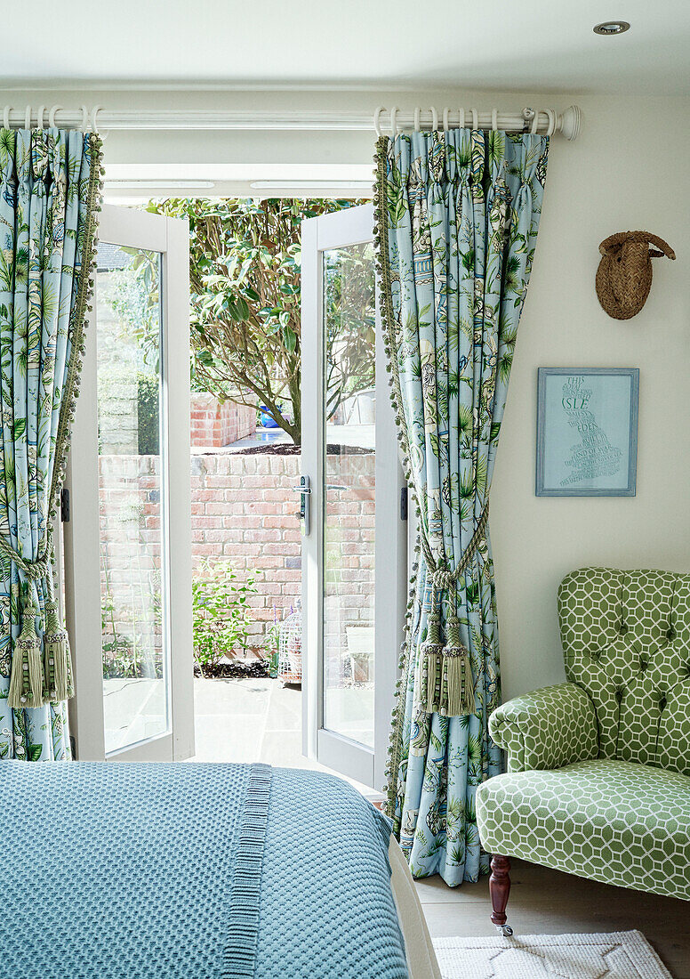 Blick durch die Gartentür zum Schlafzimmer mit kontrastierenden Stoffen in einem Cottage in den Cotswolds , UK