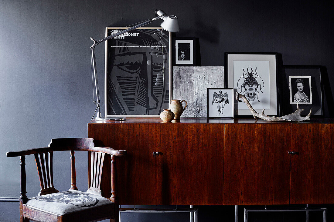 Desk lamp and framed prints on wooden sideboard with antique chair in Ramsgate home Kent, UK