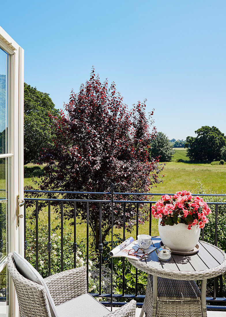 Chair and table on balcony terrace with view of fields from York home, UK