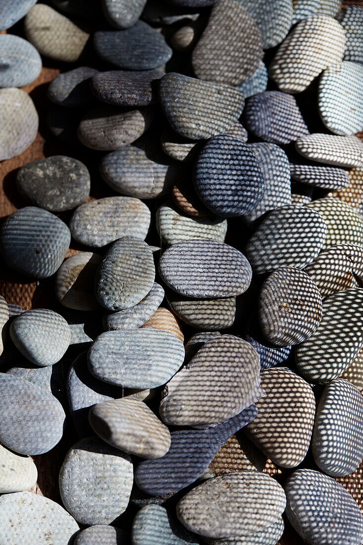 Assorted pebbles with sunlit mesh pattern in converted shipping container in Bedford, UK