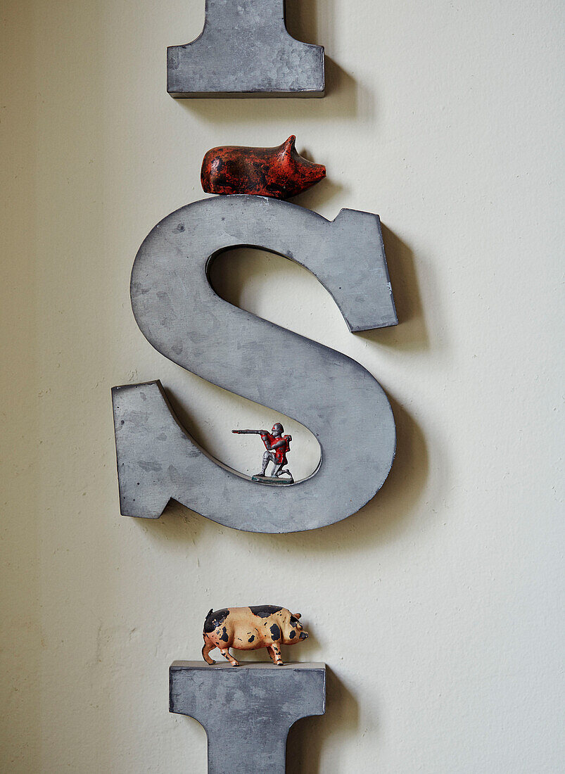 Spielzeugschweine und -soldaten mit dem Buchstaben 'S' an der Wand in einem Haus in Devon, UK