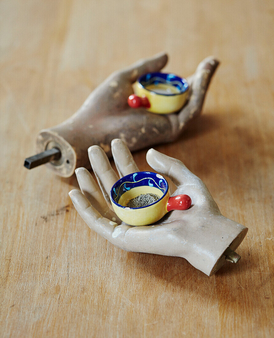 Salt and pepper bowls on mannequins hands on Devon tabletop, UK