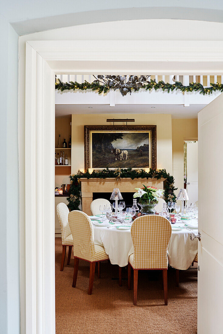 View through doorway to table set for Christmas dinner in Cotswolds home, UK