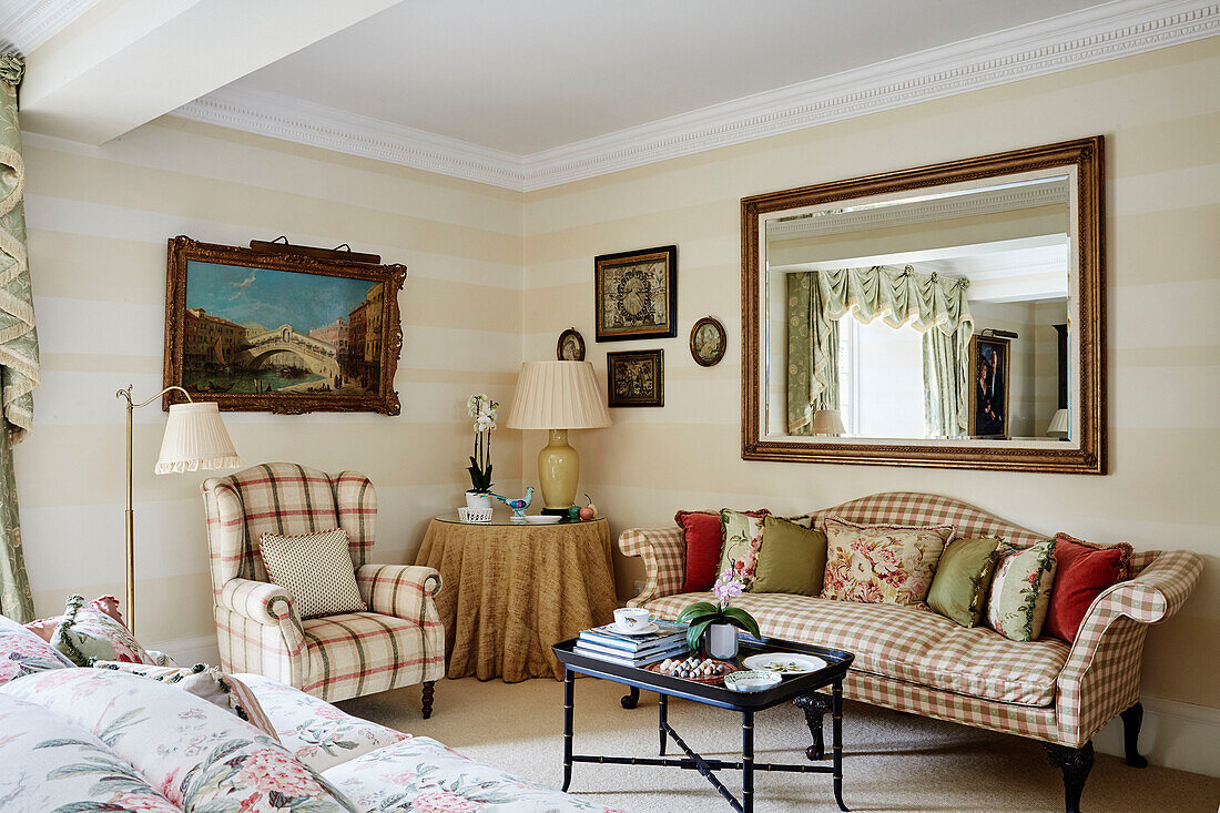 Großer Spiegel über kariertem Sofa mit Kissen in einem Haus in den Cotswolds, UK