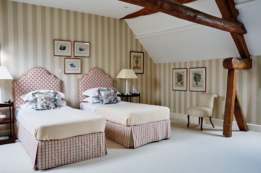 Zwei Einzelbetten in einem Zimmer mit gestreifter Tapete und Holzbalken in den Cotswolds, UK