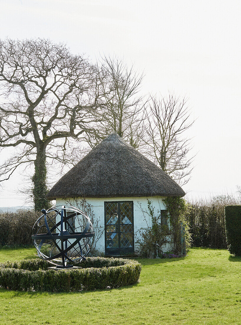 Reetgedecktes Sommerhaus und Gartenlaube auf dem Grundstück eines Hauses in Devon, UK