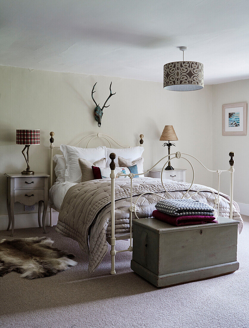 Gefaltete Decken am Fußende eines Bettes mit Metallrahmen in einem Haus in Devon, UK