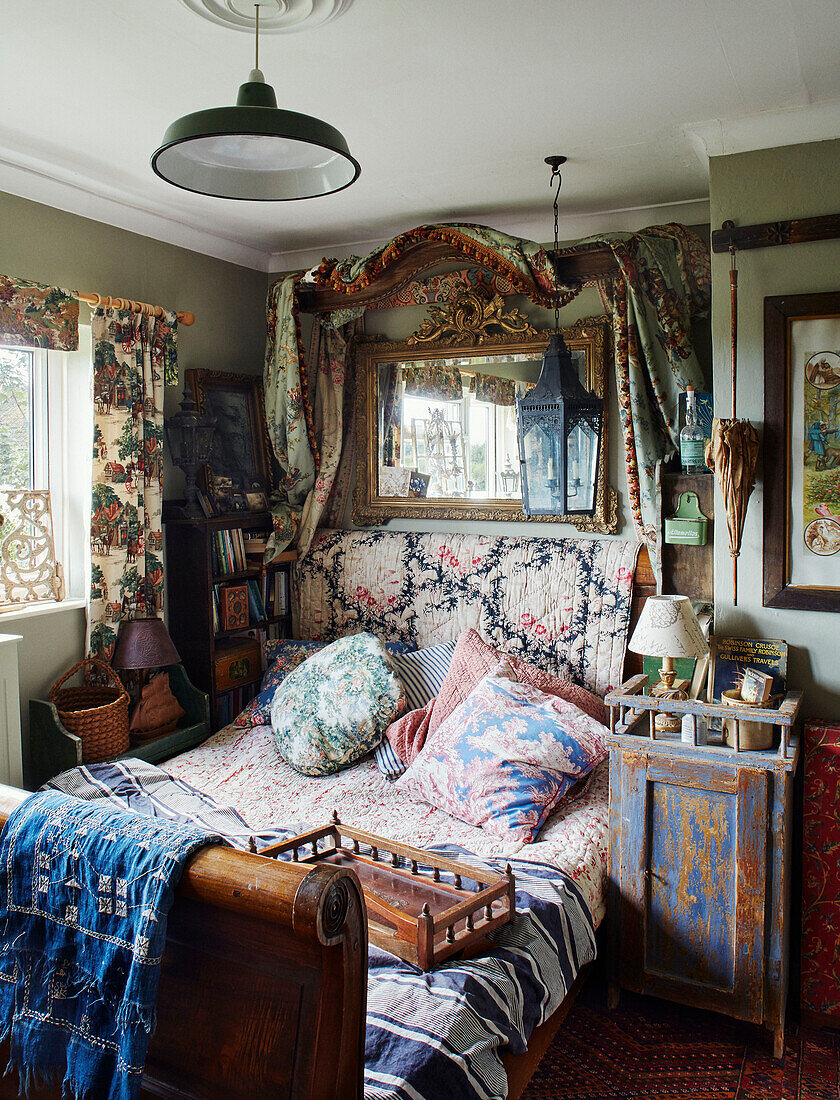 Antikes Bett mit verschiedenen Stoffen und Spiegel in einem Haus in Somerset, UK