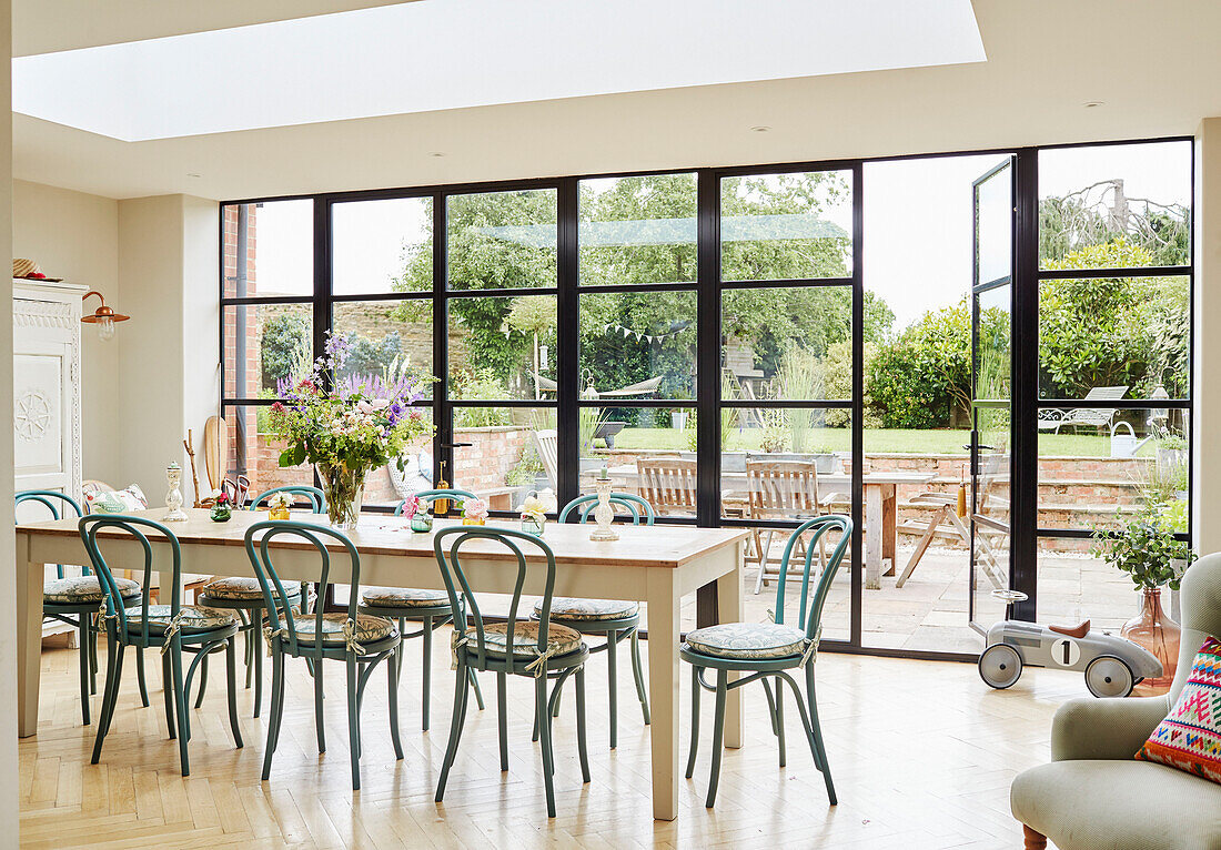 Esstisch und Stühle in einem Anbau mit Blick auf den Garten in Oxfordshire Erweiterung, UK