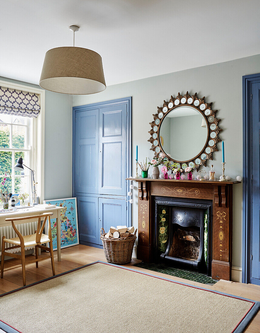 Light blue paintwork and large antique mirror above decorative fireplace in Oxfordshire home, UK