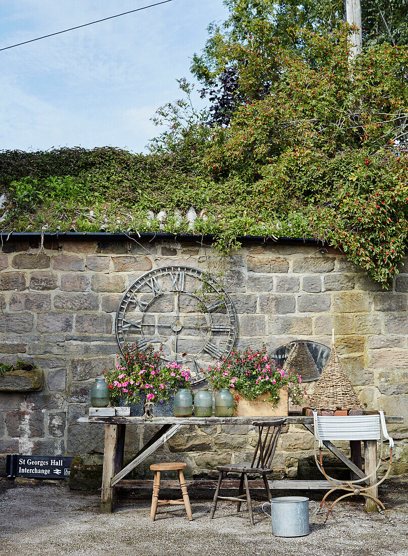 Bewachsenes Dach mit römischer Uhr und Holztisch im Hofgarten North Yorkshire, UK