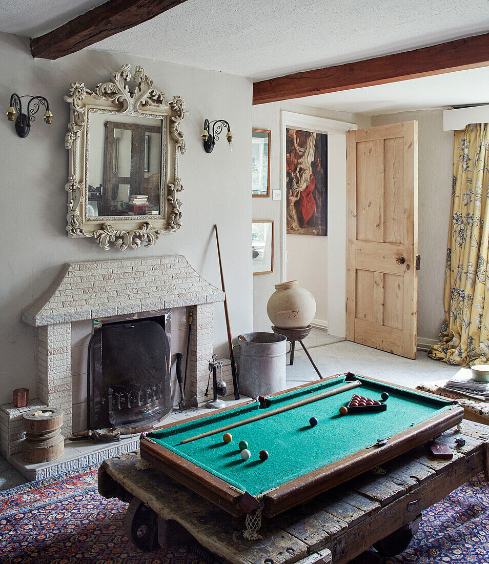 Kleiner Billardtisch mit dekorativem Spiegel über dem Kamin in einem Bauernhaus in North Yorkshire, UK