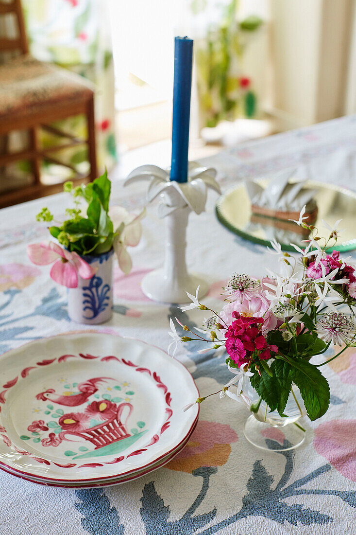 Cut flowers plate and candle on table in Oxfordshire farmhouse, UK