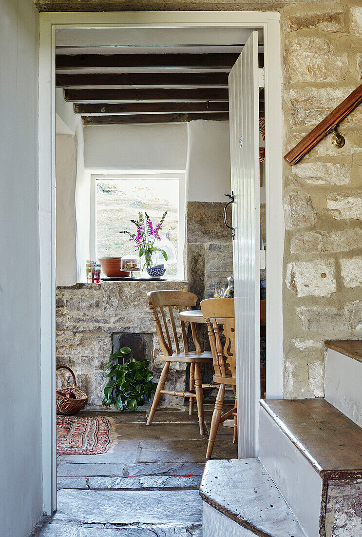 Exposed stone staircase with view through doorway in renovated Yorkshire farmhouse, UK