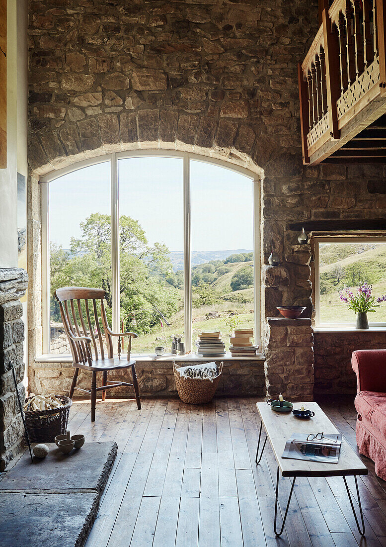 Stuhl am Fenster mit doppelhohem Zwischengeschoss aus Naturstein in einem renovierten Bauernhaus in Yorkshire, UK