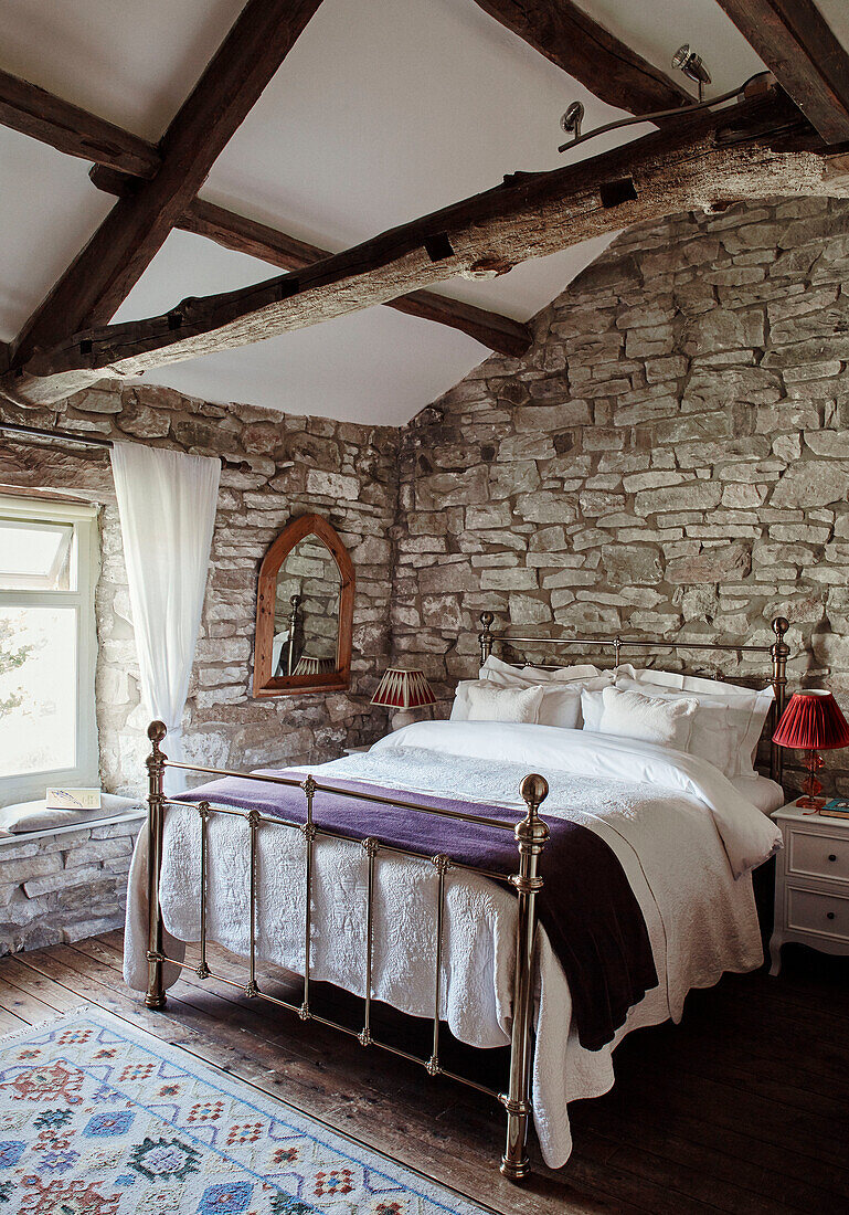 Metallrahmenbett mit freiliegenden Steinwänden in einem renovierten Bauernhaus in Yorkshire, UK