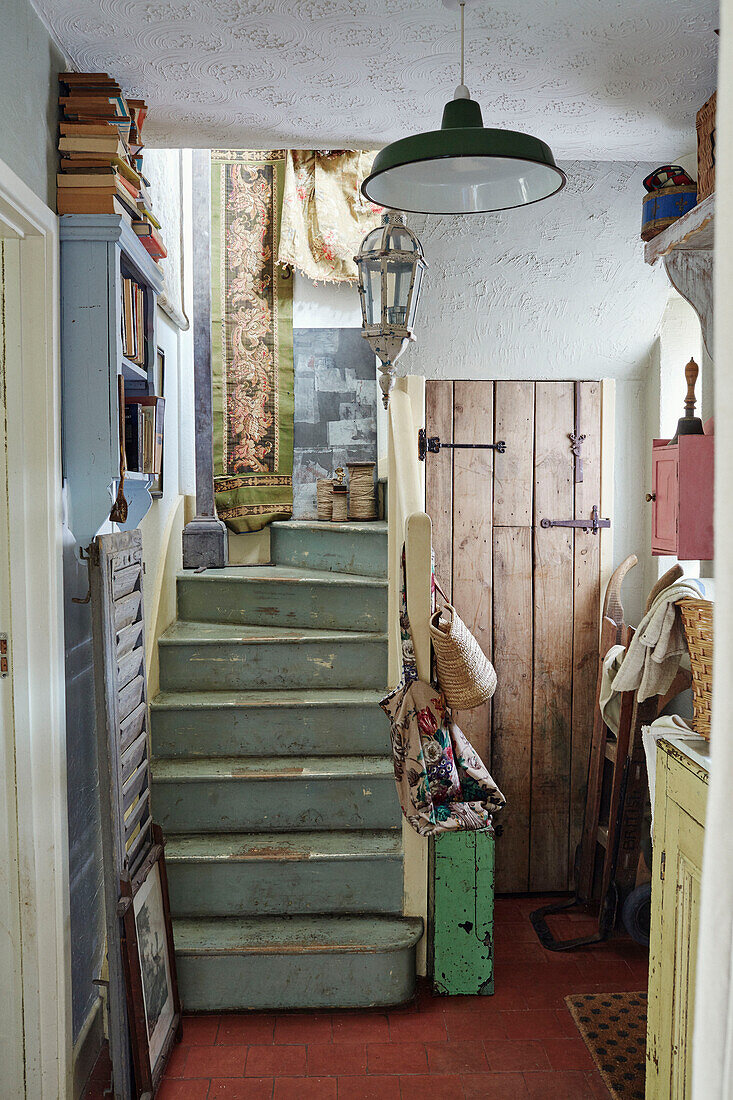Bookshelf and barrow in Somerset entrance hall with green painted stairs, UK