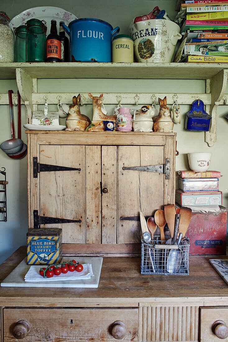 Küchenutensilien und Ornamente mit Büchern auf einem Regal über einer Holzarbeitsplatte in Somerset, UK