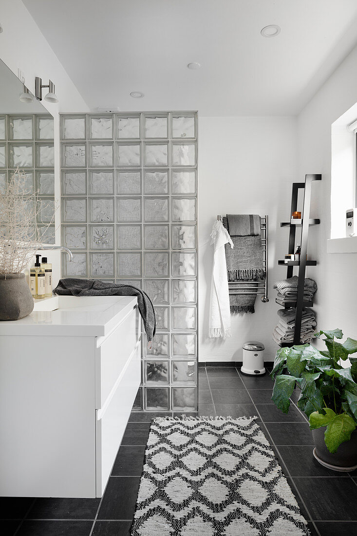 Modern black-and-white bathroom with partition of glass bricks