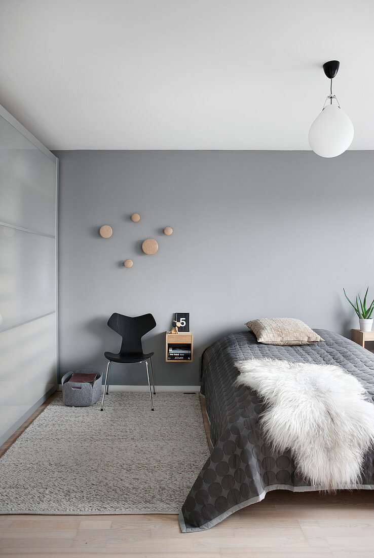 Sheepskin rug on bed in simple bedroom in shades of grey