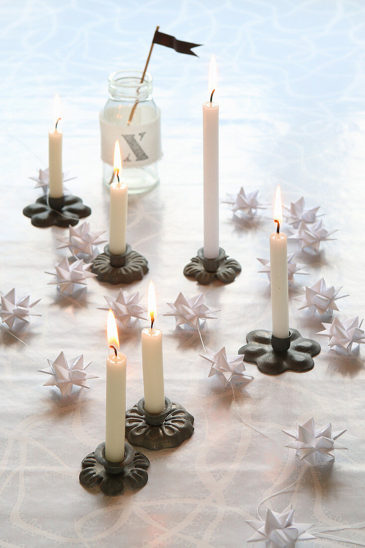 Christmas arrangement of miniature candlesticks and white origami stars
