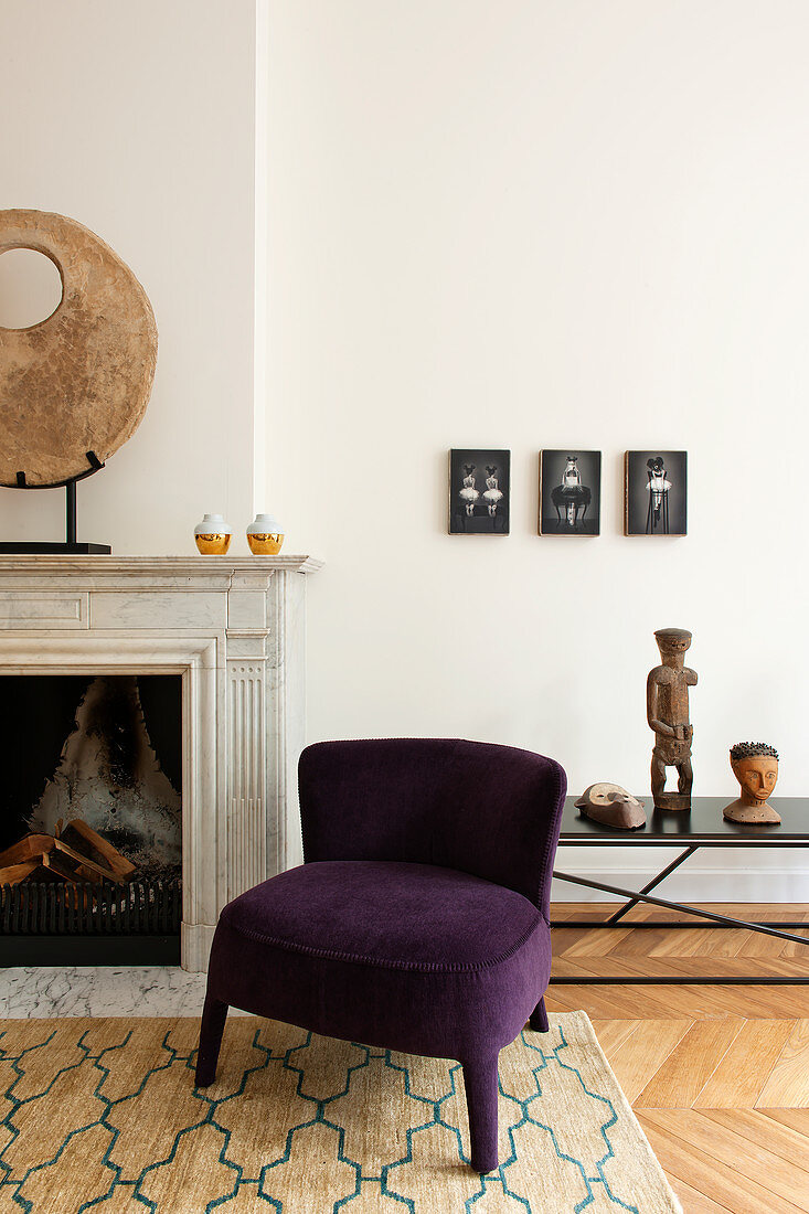 Purple easy chair next to sculpture on mantelpiece in living room