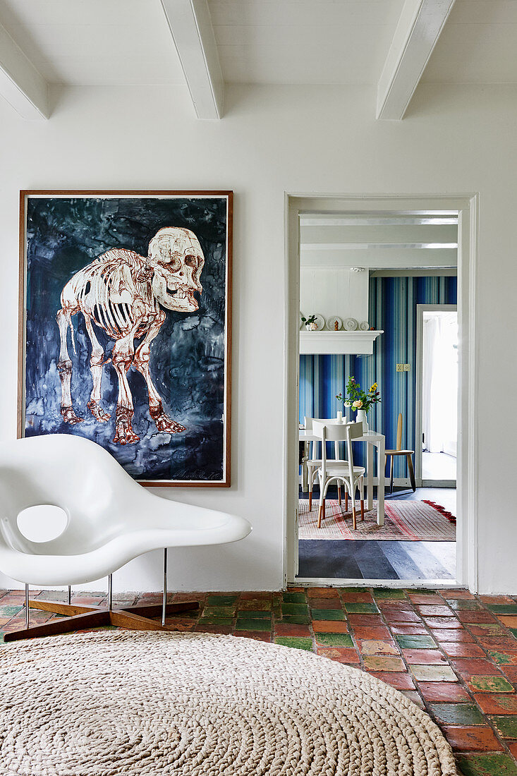 Designer chair on terracotta floor tiles and modern artwork on wall