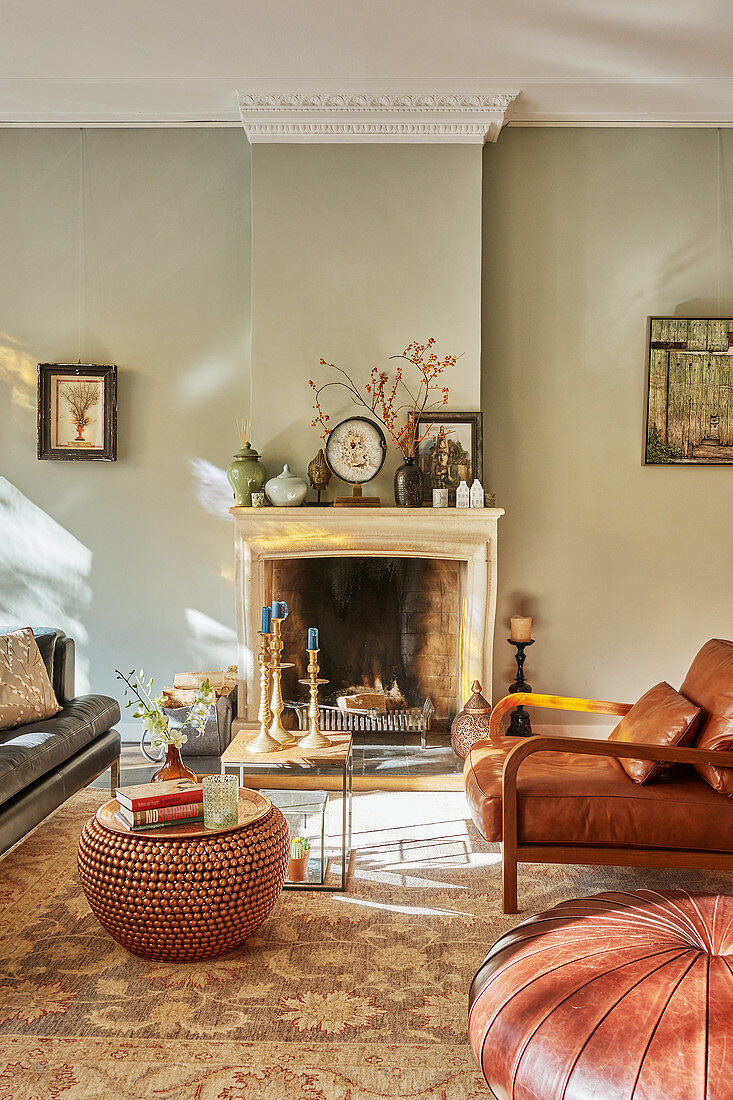 Open fireplace and leather armchair in sunny living room in earthy shades