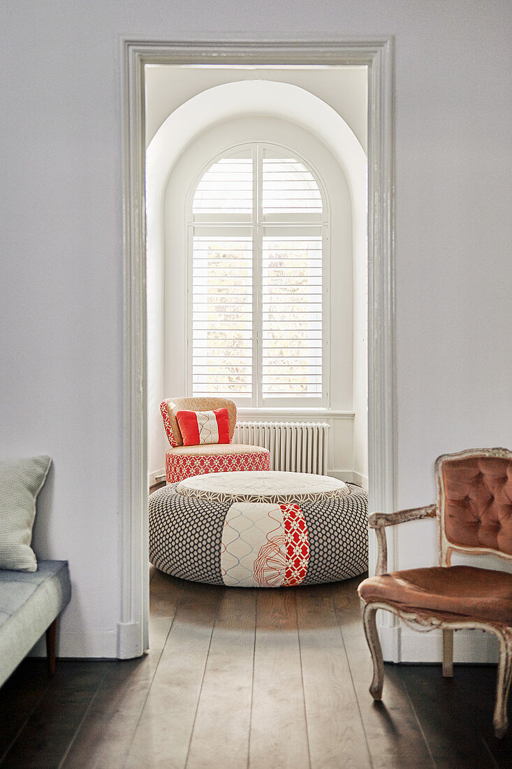 Durchgang im Wohnzimmer, Sitzpouf und Sessel vorm Bogenfenster
