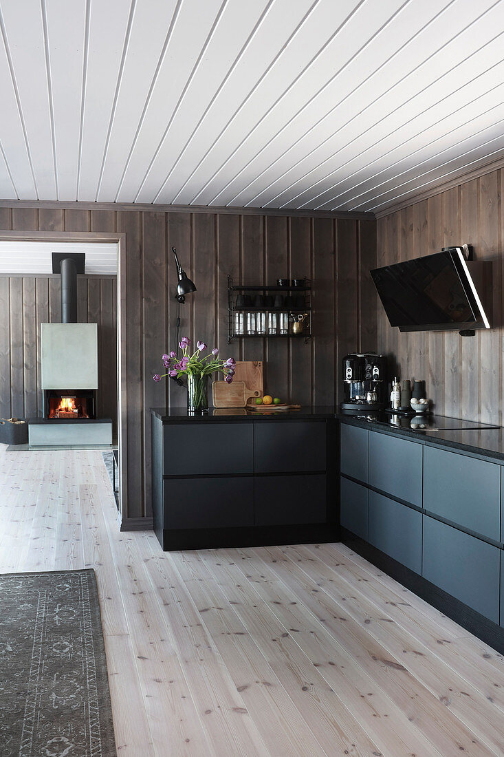 Moderne offene Küche mit rauen Fronten im Holzhaus mit Kaminofen