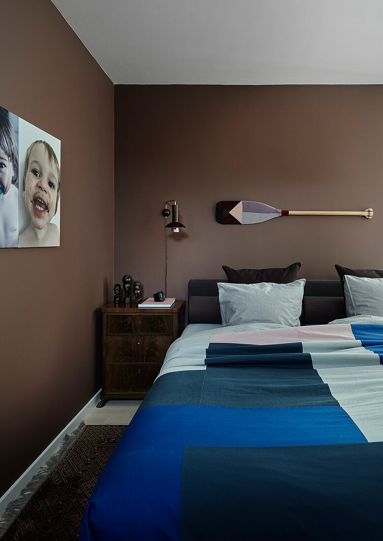 Doppelbett und Nachtkästchen im Schlafzimmer mit brauner Wand
