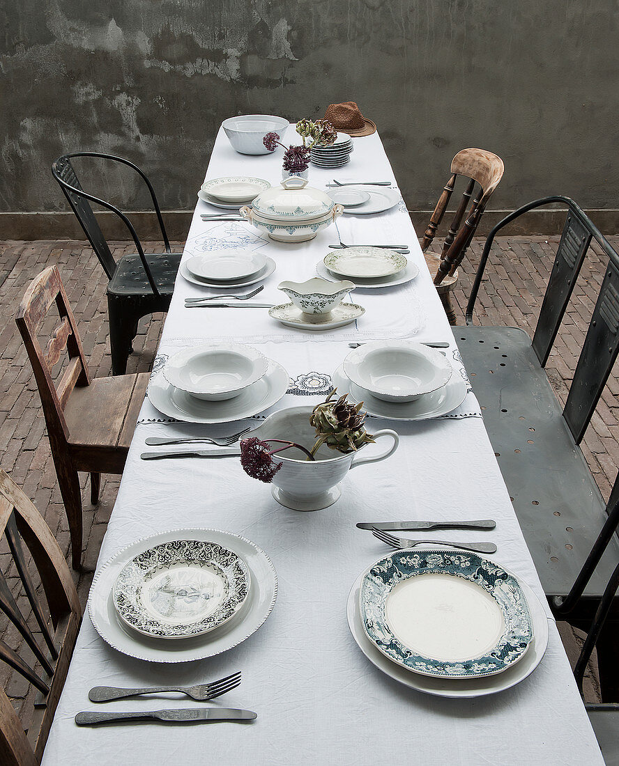 Blick auf gedeckte Tisch mit weißer Tischdecke und verschiedenen Stühlen
