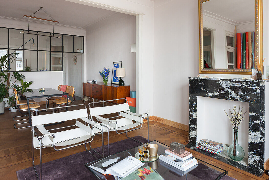 Living room with marble fireplace, white armchairs and parquet flooring