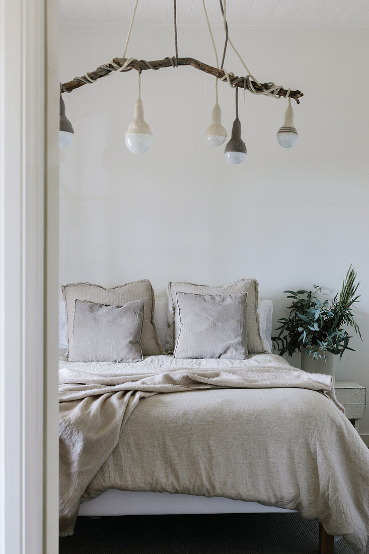 Pendant lights on a branch above the bed in the simple bedroom