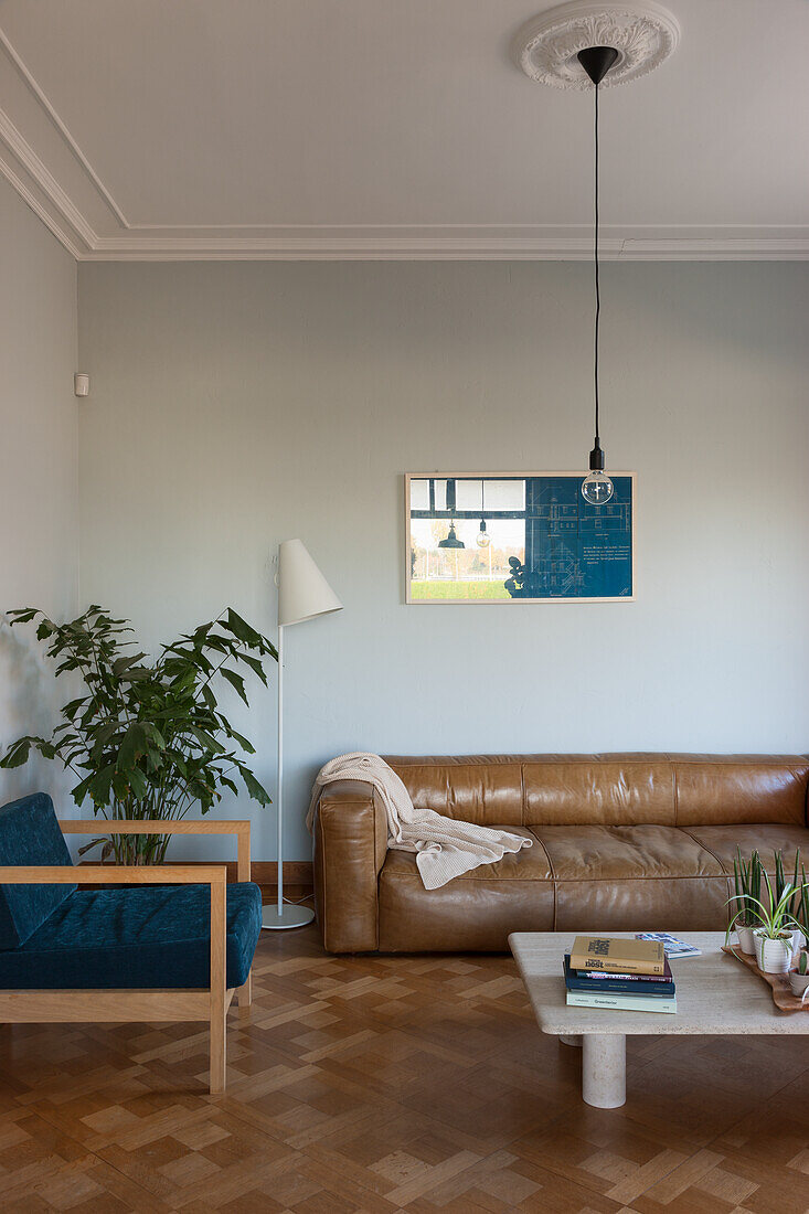 Living room with leather sofa, blue armchair and parquet flooring