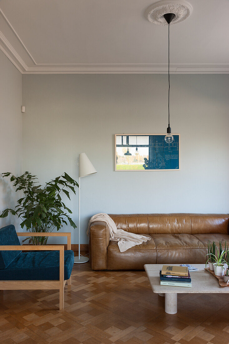 Wohnzimmer mit Leder-Sofa, blauem Sessel und Parkettboden