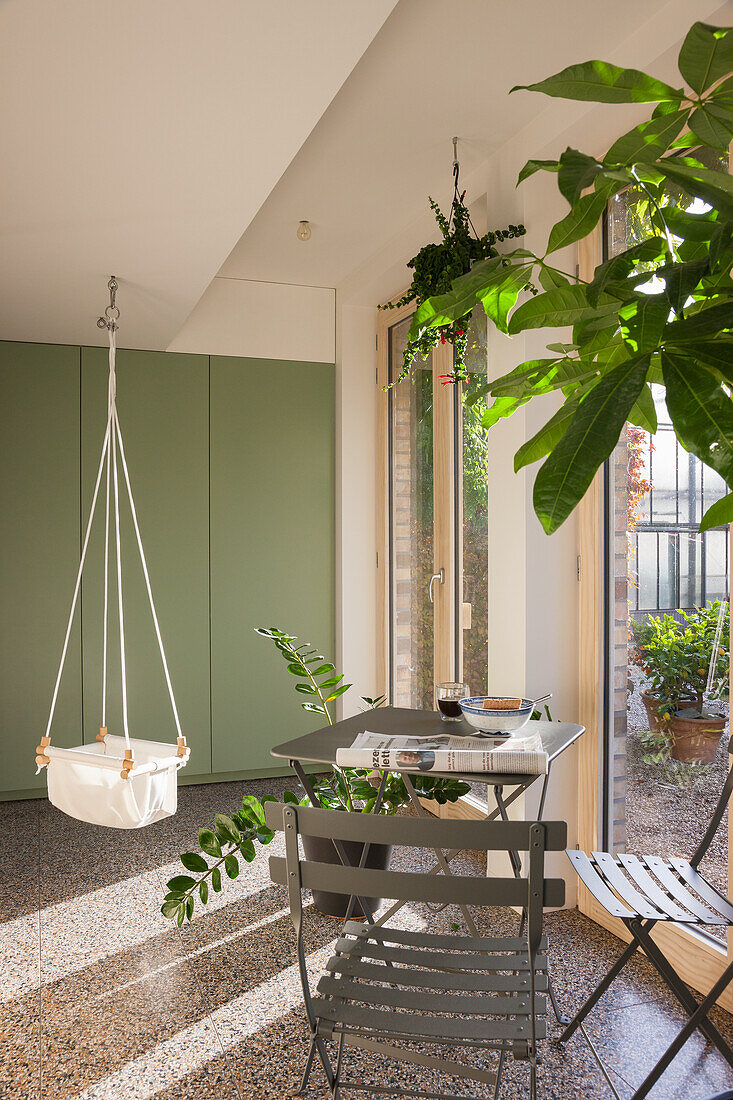 Hängesessel und kleiner Bistrotisch im hellen Wintergarten