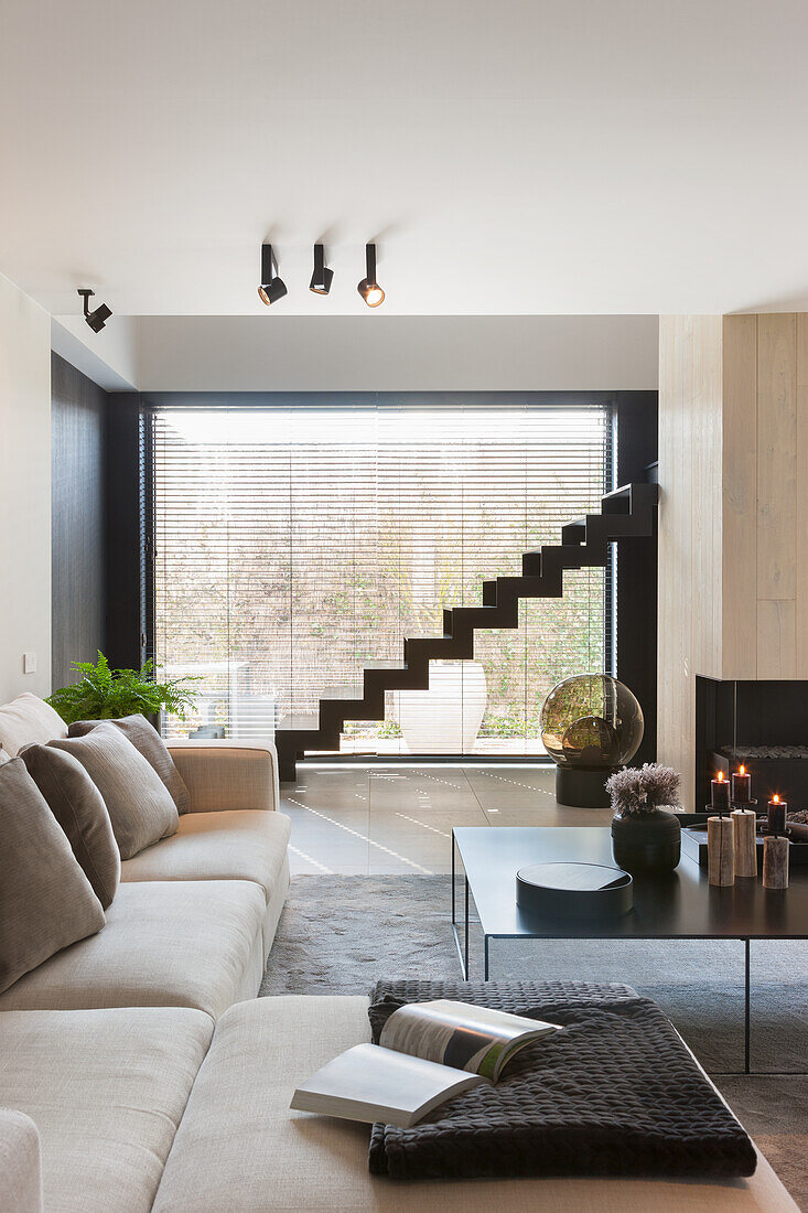 Living room with beige sofa and staircase in front of large window