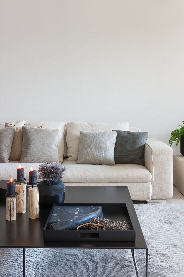 Beige sofa with pillows and coffee table with candles in the living room