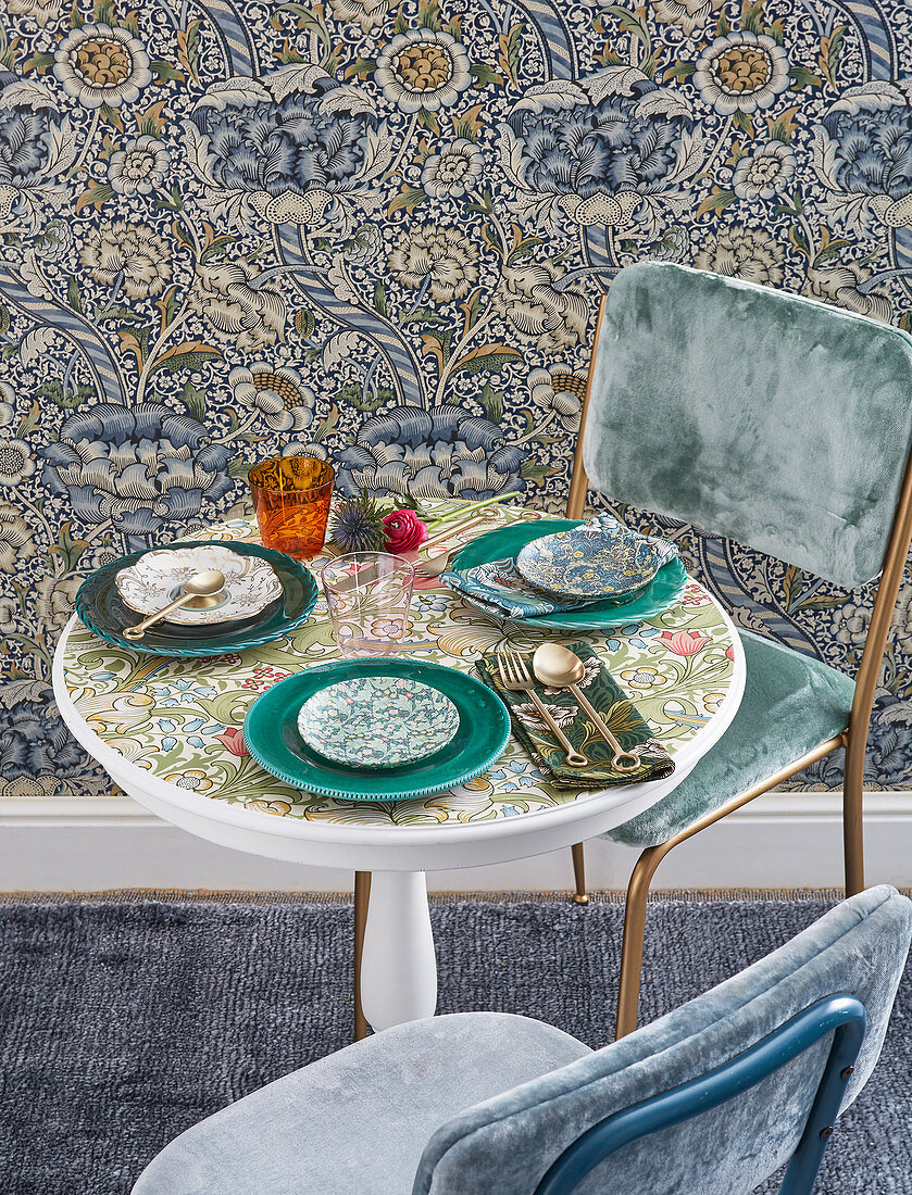 Gedeckter Tisch mit geblümter Platte vor Vintage Blumentapete