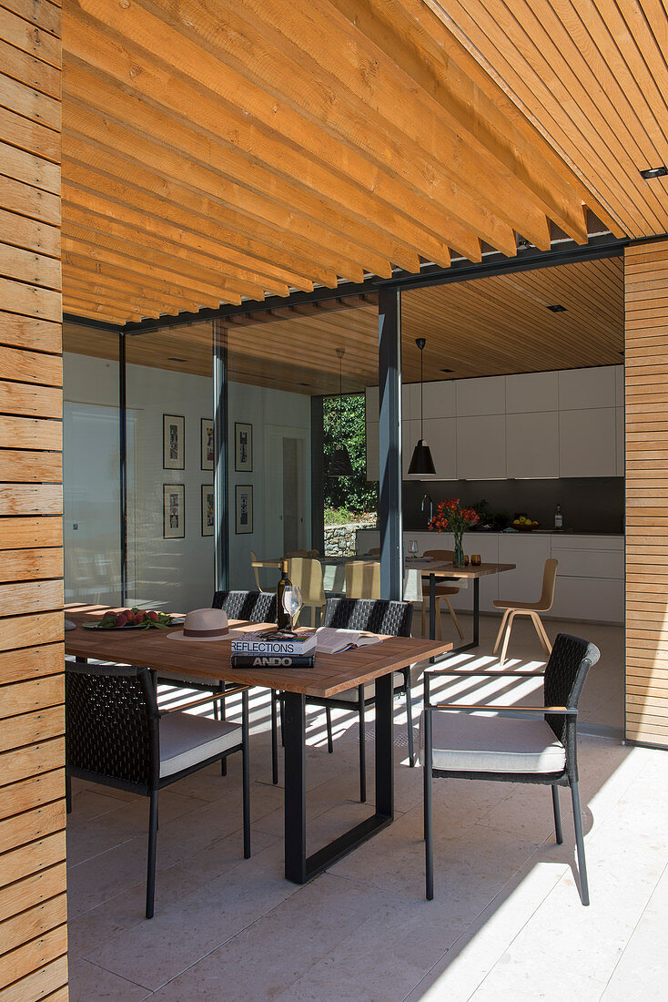 Esstisch auf überdachter Terrasse am modernen Architektenhaus