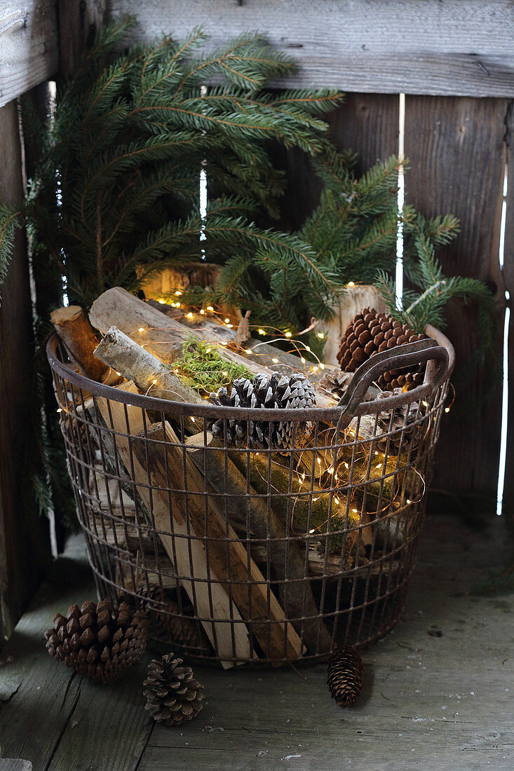 Firewood, pine cones and fairy lights in wire basket