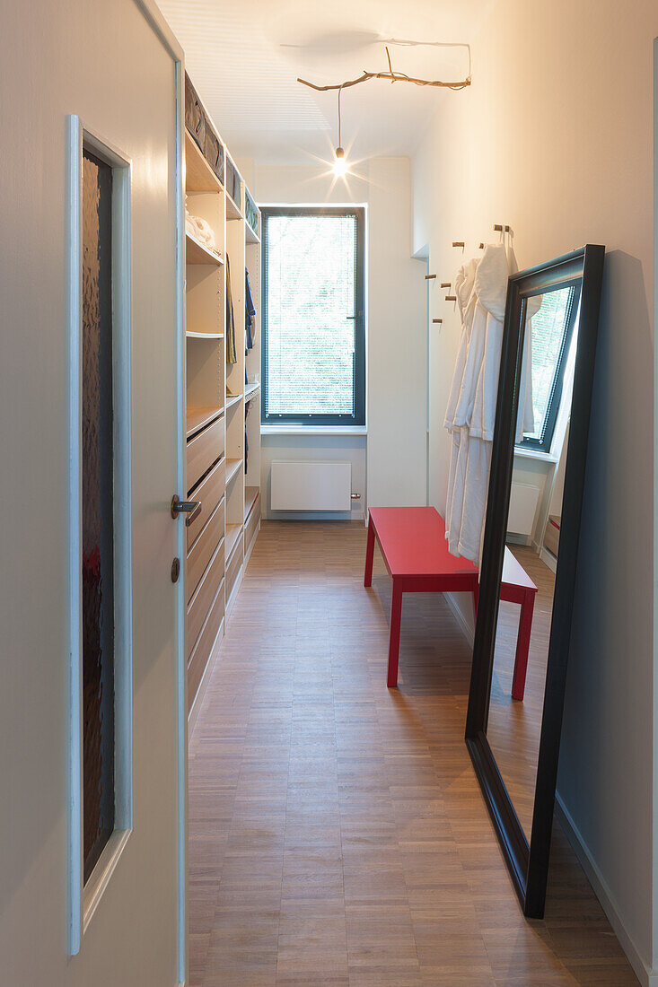 Dressing room with fitted wardrobes, wall mirror and red bench seat