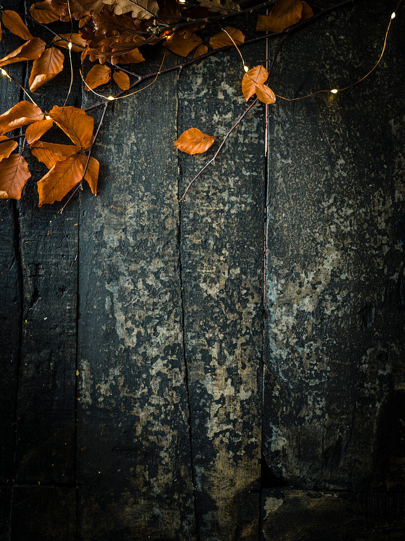 Dunkler Holzuntergrund mit Herbstblättern